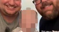 Brandon Riley-Mitchell (right), 39, and his husband were seen in a video holding their infant child and blowing out candles on a series of cupcakes