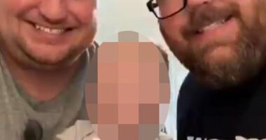 Brandon Riley-Mitchell (right), 39, and his husband were seen in a video holding their infant child and blowing out candles on a series of cupcakes