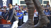 Former New England Patriots quarterback Tom Brady, left, looks at a bronze statue of himself after it was unveiled in Patriot Place Plaza on Friday