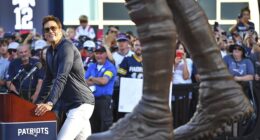 Former New England Patriots quarterback Tom Brady, left, looks at a bronze statue of himself after it was unveiled in Patriot Place Plaza on Friday