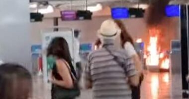 Stunned holidaymakers look on towards a fire lit in Terminal 1 of Milan Malpensa airport