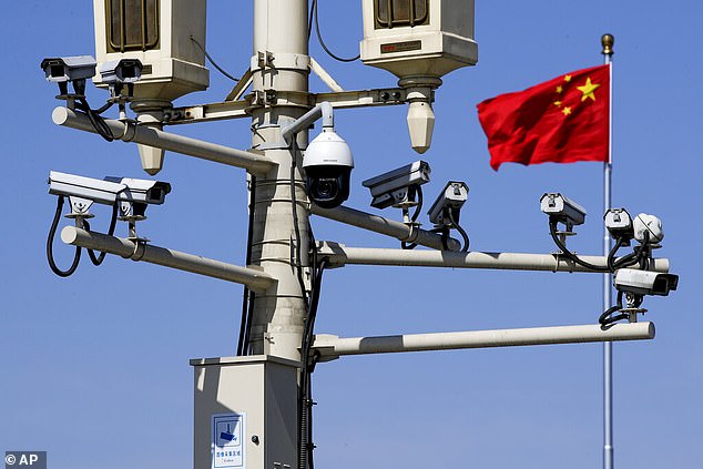 A Chinese national flag flutters near the surveillance cameras mounted on a lamp post in Tiananmen Square in Beijing