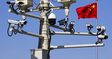 A Chinese national flag flutters near the surveillance cameras mounted on a lamp post in Tiananmen Square in Beijing