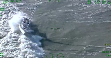 A yacht is seen being thrown around by waves off the coast of Newhaven in East Sussex