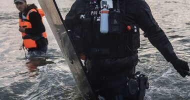 French Police enter the water to try and stop migrants boarding small boats that had come to collect them from further down the coastline on June 13, 2025