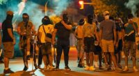 Protesters wearing masks and balaclavas hold chains, sticks and baseball bats during the fourth night of riots on July 14, 2025 in Torrepacheco, in the province of Murcia, Spain