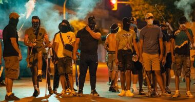 Protesters wearing masks and balaclavas hold chains, sticks and baseball bats during the fourth night of riots on July 14, 2025 in Torrepacheco, in the province of Murcia, Spain