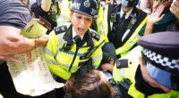 A demonstrator is led away by police officers as people take part in a protest in support of Palestine Action in Parliament Square on Saturday