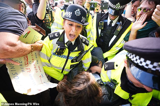 A demonstrator is led away by police officers as people take part in a protest in support of Palestine Action in Parliament Square on Saturday