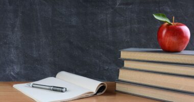 books and apple on teacher’s desk