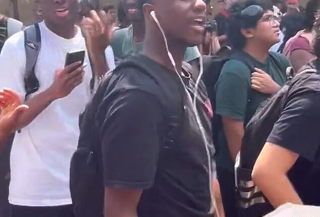 A Texas State University student (front, in black t-shirt) has been expelled after he repeatedly reenacted Charlie Kirk's assassination at an on-campus memorial