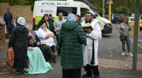 Members of the local Jewish community stand in the street outside Heaton Park synagogue following the terrorist attack
