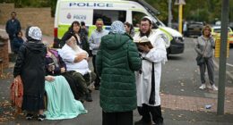 Members of the local Jewish community stand in the street outside Heaton Park synagogue following the terrorist attack