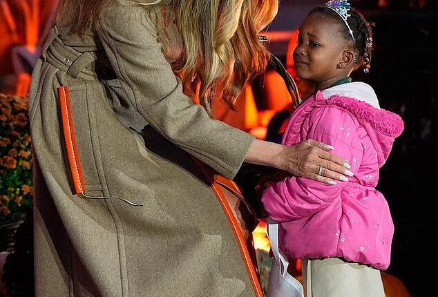 Melania Trump, 55, showed off her maternal side while handing out candy, comforting a young girl who looked frightened at the Halloween decor surrounding her