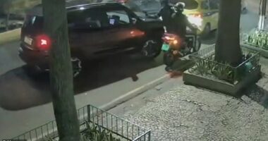 This is the moment an armoured Jeep driver rams into two armed robbers trapping them beneath her vehicle after they tried to hold her up in the street. Pictured: The attempted robbery taking place