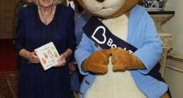 Queen Camilla is pictured beaming next to Peter Rabbit at an event at Clarence House today as she poses with the new book, Four Happy Bunnies