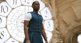 Ncuti Gatwa in a blue and white outfit standing in front of a clock in Doctor Who