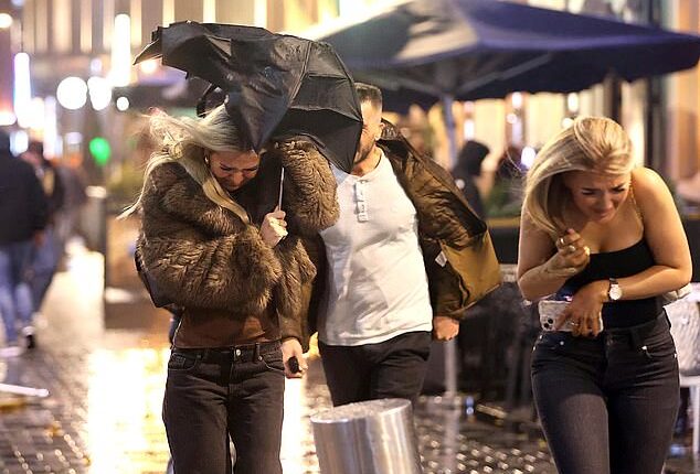 Strong winds up to 100mph were recorded across the UK. Pictured: Revellers face stormy weather on a night out in Leeds on Friday