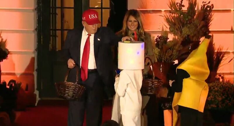 President Donald Trump brought Halloween joy to children by handing out candy at the White House and rehashing a party trick from 2019 by patting a child's head with a bar of chocolate. Trump arrived back at the White House Thursday evening from a whirlwind trip to Asia in time to celebrate spooky season with his wife Melania. Around 6pm ET the Trumps emerged from the White House ¿s southern entrance to Michael Jackson¿s ¿Thriller¿ being played by a military string ensemble. The duo delighted children who lined up decked out in costumes to meet with them.
