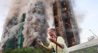 A man reacts, as smoke rises while flames engulf bamboo scaffolding across multiple buildings at Wang Fuk Court housing estate, in Tai Po, Hong Kong, China, November 26, 2025