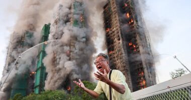 A man reacts, as smoke rises while flames engulf bamboo scaffolding across multiple buildings at Wang Fuk Court housing estate, in Tai Po, Hong Kong, China, November 26, 2025