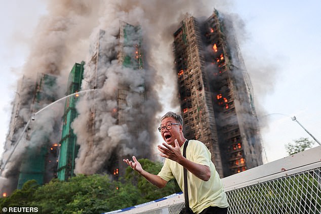 A man reacts, as smoke rises while flames engulf bamboo scaffolding across multiple buildings at Wang Fuk Court housing estate, in Tai Po, Hong Kong, China, November 26, 2025