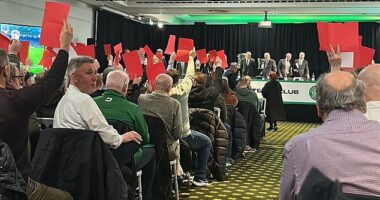 Celtic supporters attending the agm wave red cards at the board as they take their seats