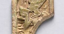 The artifact, labeled ECM 1887, depicts King Tut drinking from a white lotus cup while wearing a blue crown with a cobra on it, a wide necklace, bracelets, armbands and a detailed pleated kilt