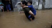 Residents wade floods at the residential areas in East Jakarta, on February 19, 2021