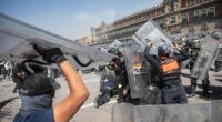 Mexico City police are seen fighting with protestors outside the National Palace on Saturday after thousands of people flocked to the official residence of the president to demand her resignation