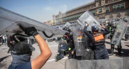Mexico City police are seen fighting with protestors outside the National Palace on Saturday after thousands of people flocked to the official residence of the president to demand her resignation