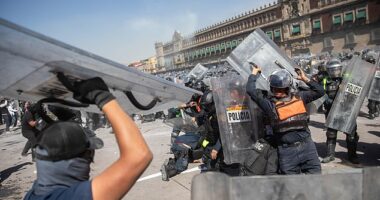 Mexico City police are seen fighting with protestors outside the National Palace on Saturday after thousands of people flocked to the official residence of the president to demand her resignation