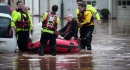 Emergency services help people stricken on a flooded street on November 15 in Monmouth, Wales