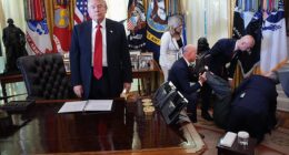 President Donald Trump (left) stands by after a drug company executive fainted in the Oval Office on Thursday