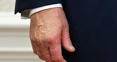 A close-up shows Donald Trump's right hand covered in heavy makeup on October 10