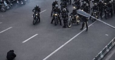 A photo of a lone demonstrator defiantly sitting on the road in front of armed security forces in Iran has gone viral on social media