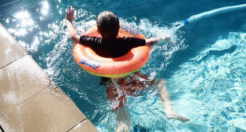 boy with floatie swims in pool
