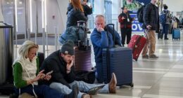 Pictured: People wait for their flight at LaGuardia Airport in Queens, New York, on Friday as a winter storm tears through the Northeast