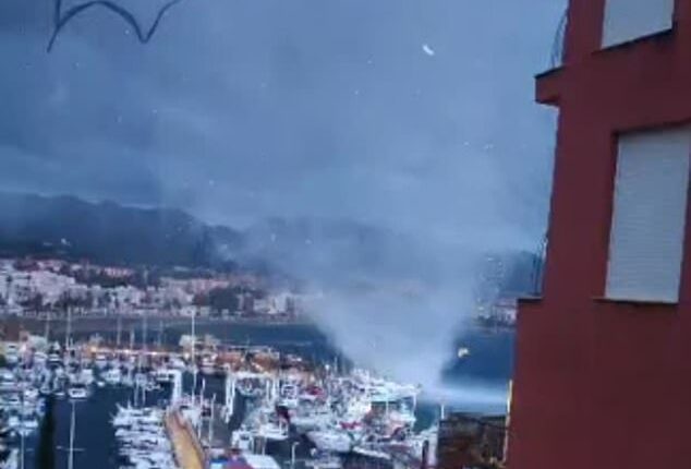 A waterspout was seen in footage tearing through a port in a Spanish holiday resort after flooding left at least one person dead