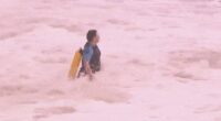 A police officer is seen running into the giant swell at Coogee Beach