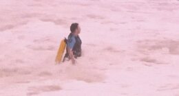 A police officer is seen running into the giant swell at Coogee Beach