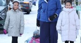 A mother walks to school with her children in the snow near Birmingham's Warley Woods today