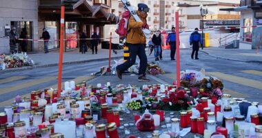 A skier passes candles near the sealed off Le Constellation bar in Crans-Montana, where at least 40 people were killed in a devastating fire during New Year's Eve celebrations