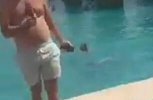 A man wearing swimming trunks at the side of the pool while strikes are intercepted above