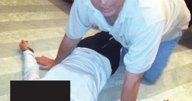 Andrew Mountbatten-Windsor kneeling over a woman lying on the floor in an image released by the Justice Department on January 30. It is not clear when the image was taken but it appears to have been at Epstein's home - and a man is seen in the background with his bare feet resting on the table