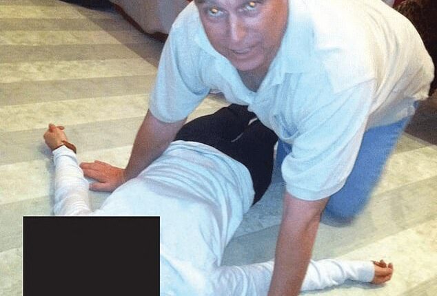 Andrew Mountbatten-Windsor kneeling over a woman lying on the floor in an image released by the Justice Department on January 30. It is not clear when the image was taken but it appears to have been at Epstein's home - and a man is seen in the background with his bare feet resting on the table