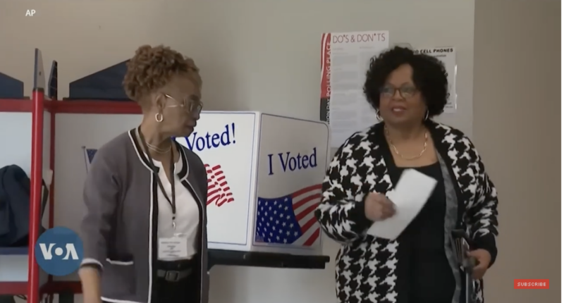 A black woman prepares to cast her ballot.