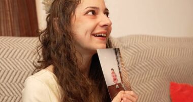 Noelia smiles as she holds up a picture from her childhood taken before her life was marked by abuse and trauma