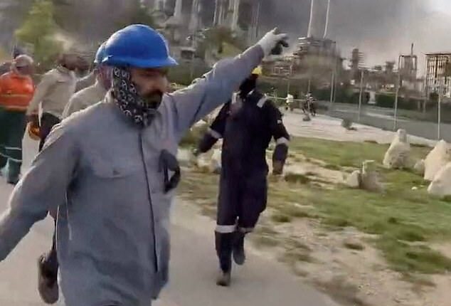 Pictured: Workers evacuate area around Saudi Aramco's Ras Tanura oil refinery as smoke rises following a reported Iranian drone strike