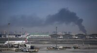 Smoke rises from Dubai International Airport on Sunday morning as Emirates planes remain grounded